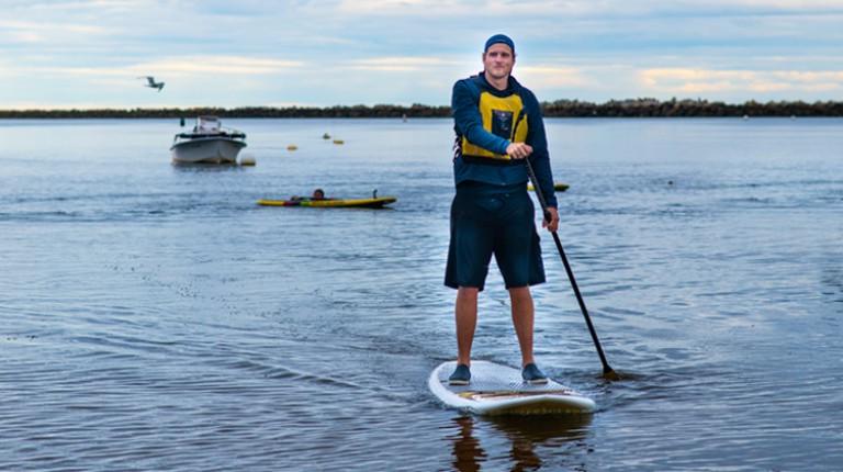 A student coming back to shore after paddle boarding